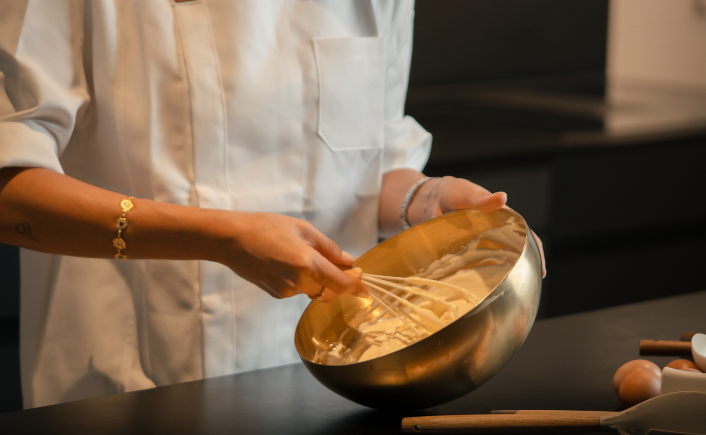 Pastry chef elegantly whisking cheesecake cream in a golden bowl.  Elegant image of the baking process of a cheesecake.