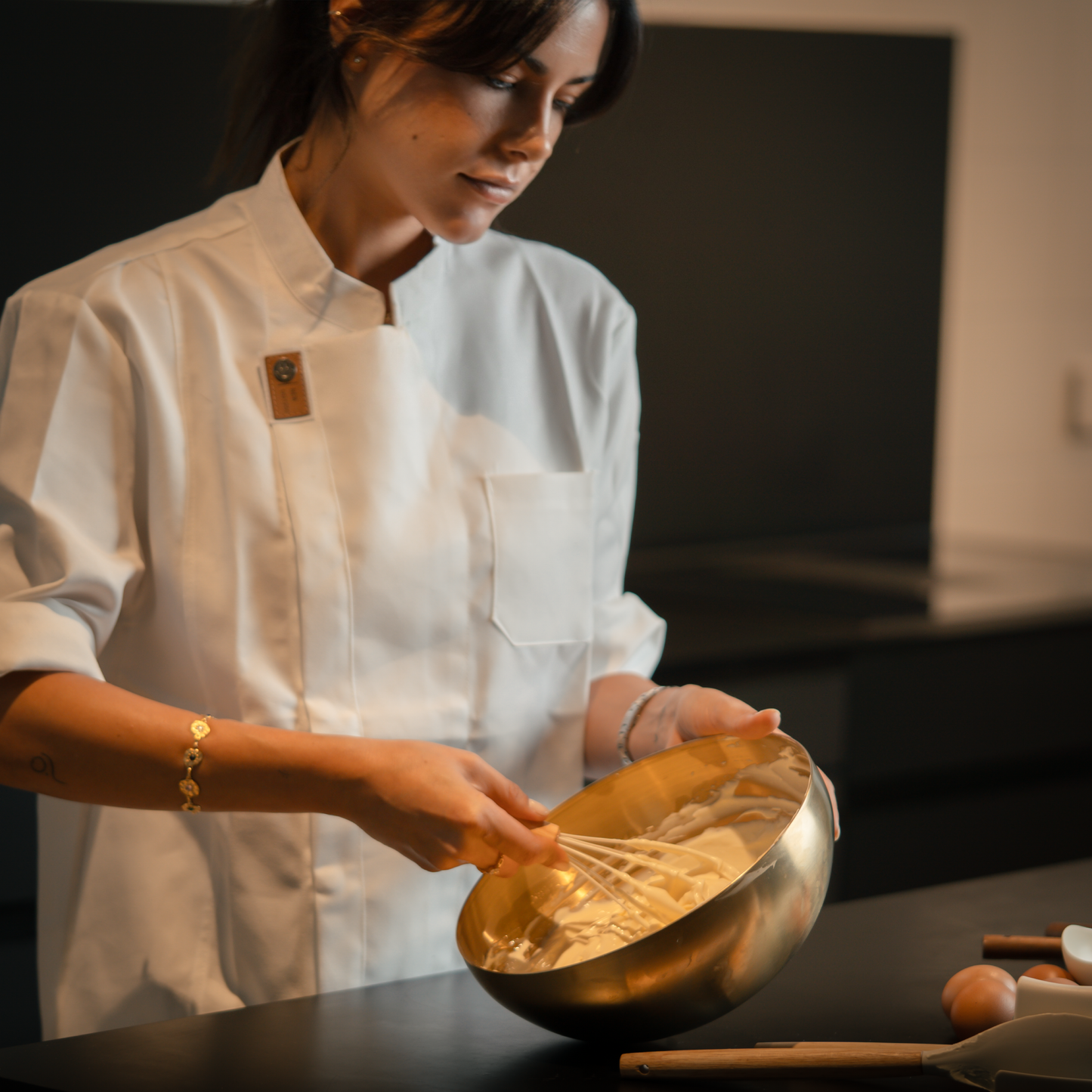 Pastry chef elegantly whisking cheesecake cream in a golden bowl.  Elegant image of the baking process of a cheesecake.