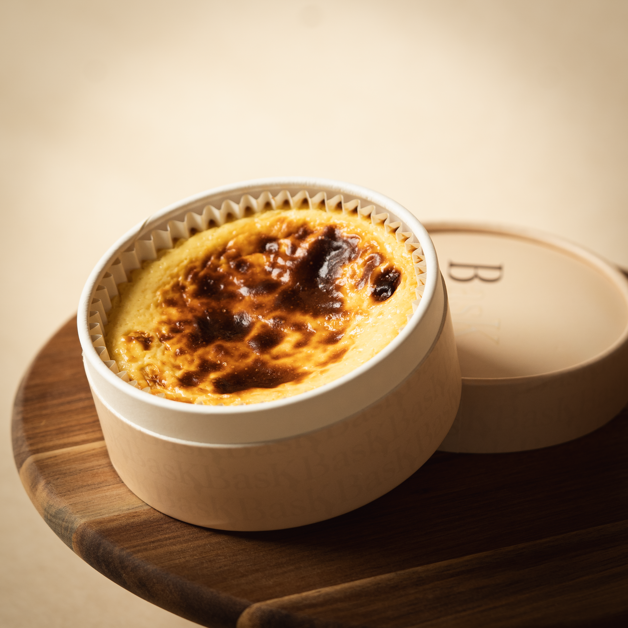Small Basque cheesecake from BasK — golden-burnt top with creamy center and delicate biscuit base. Made for one or to share. Packaged in a premium round beige box.
